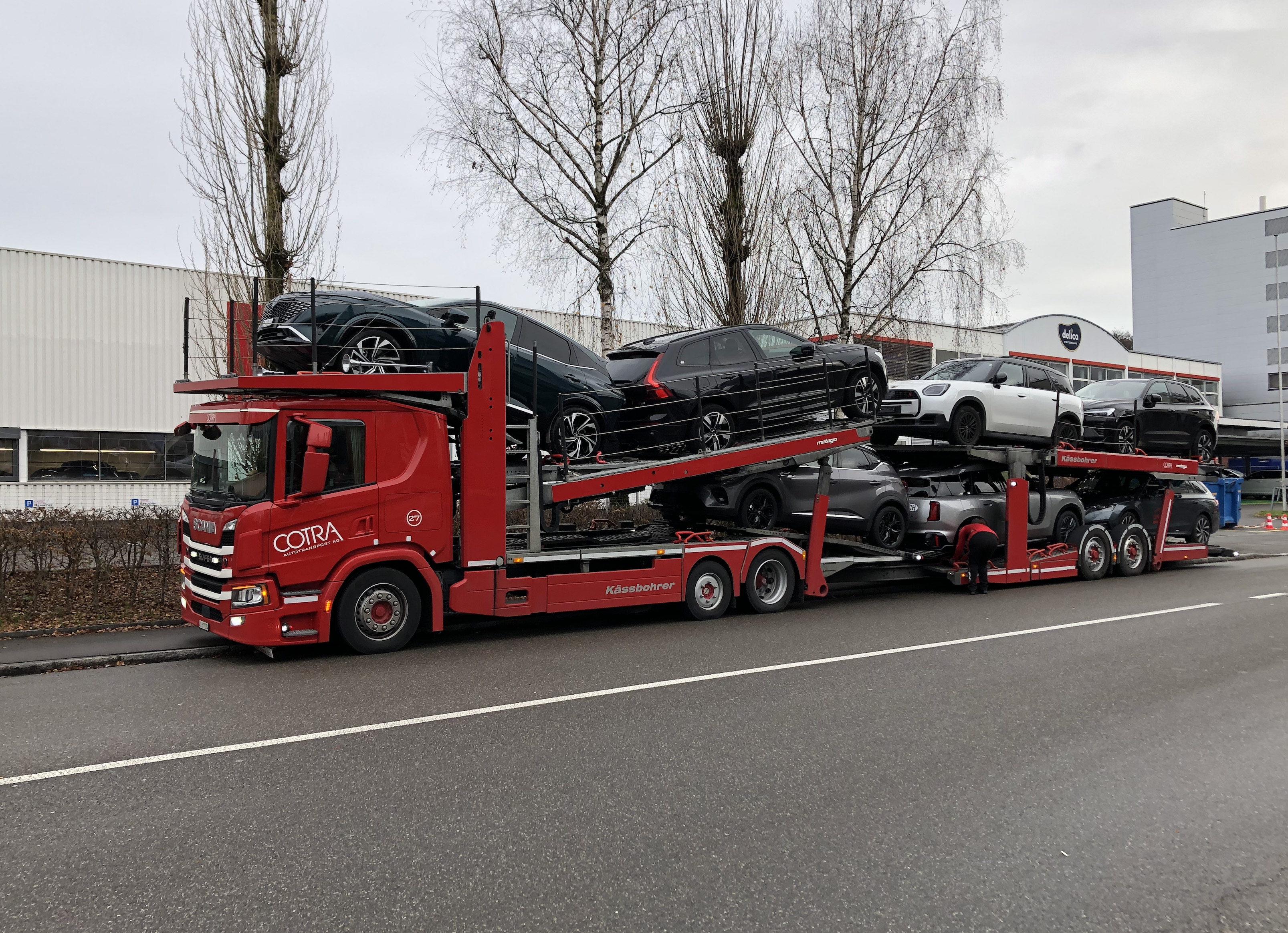 Een beladen autotransporter met moderne Volvo-modellen en andere Europese voertuigen